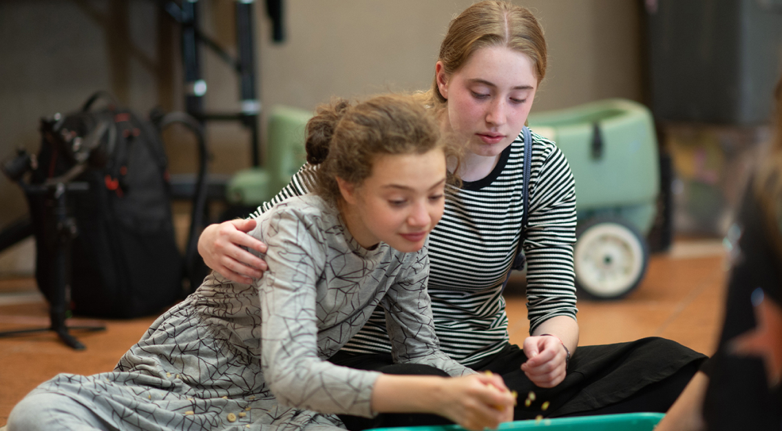 Two girls are sitting on the floor, engaged in a joint activity.