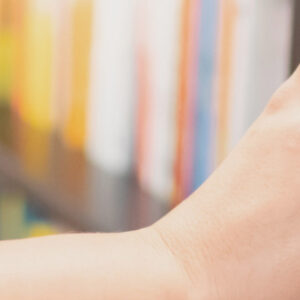 Hand taking records or book soff shelves.