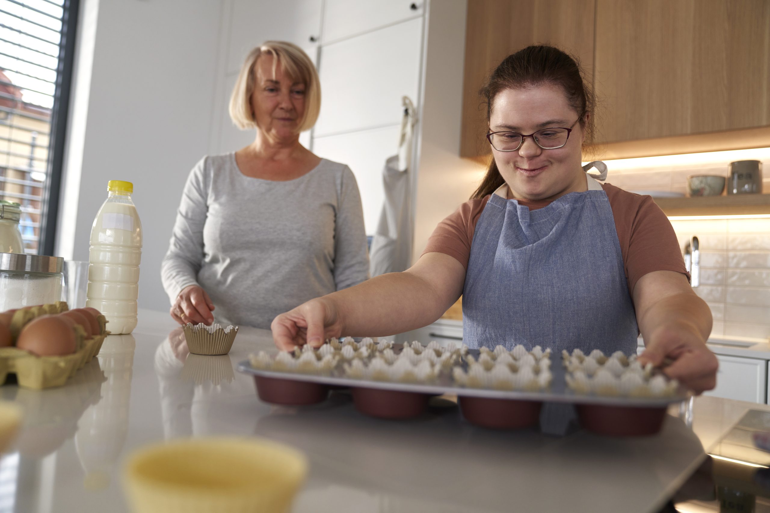 Woman with down syndrome holding tray with homemade cupcakes.