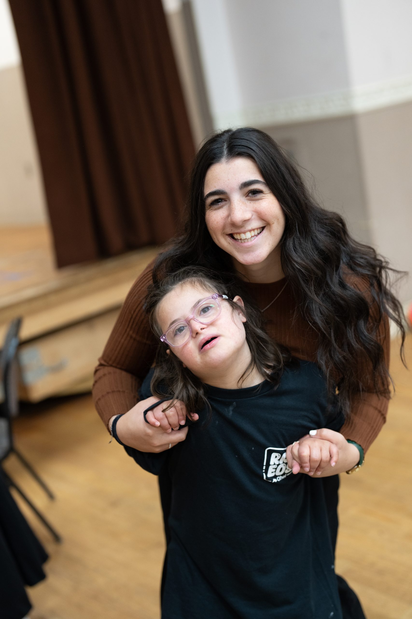 Smiling young woman hugging child with developmental disabilities.