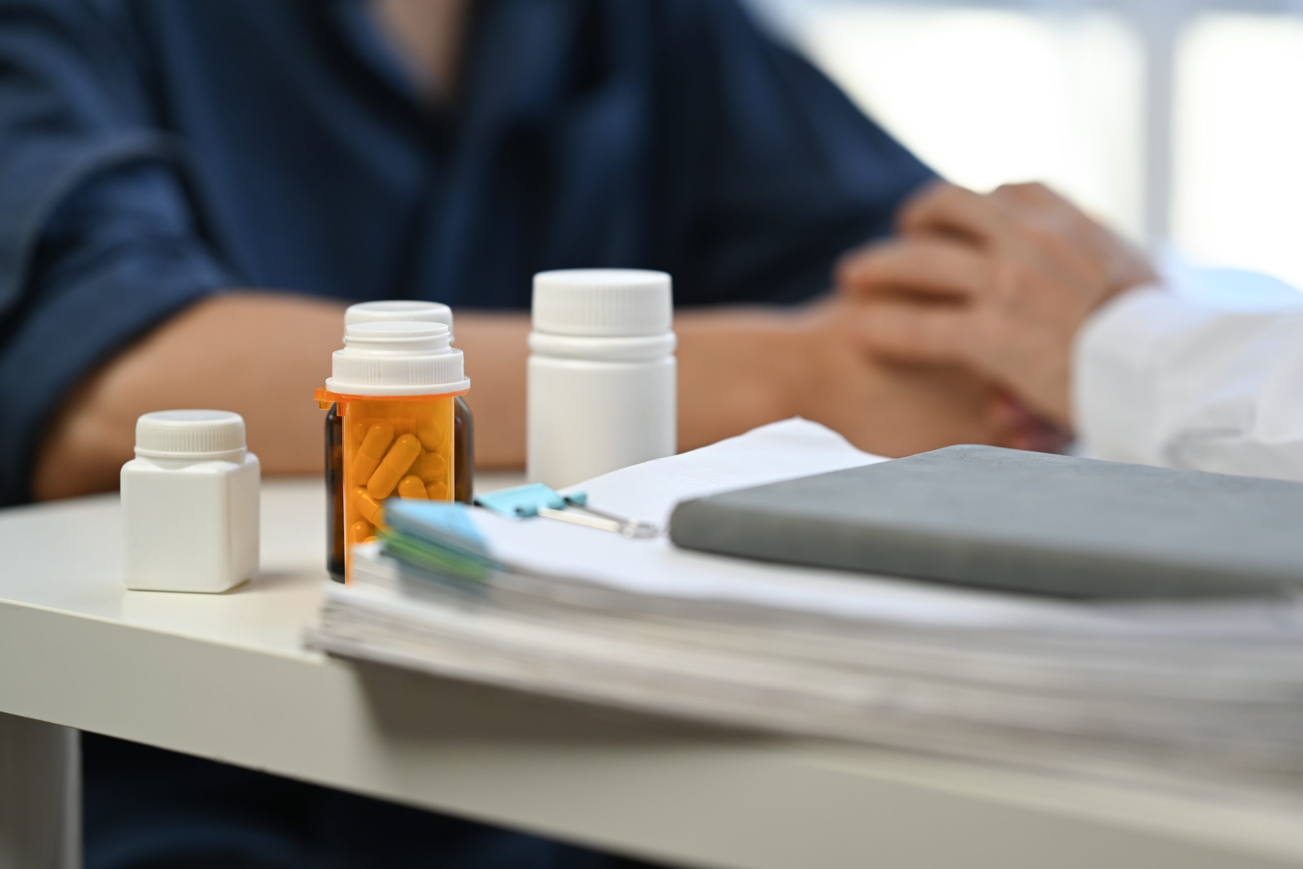 Pills bottles and medical records on table in clinic. Medical insurance, health care concept.