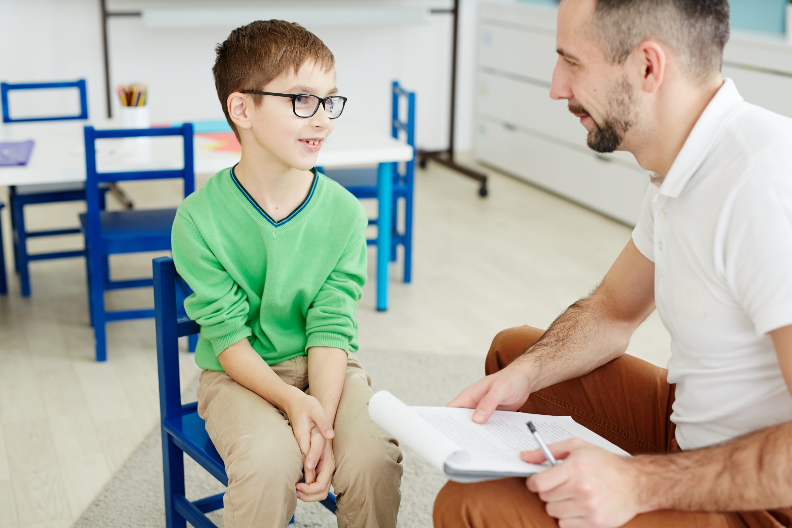 School boy answering questions of a therapist at individual session.