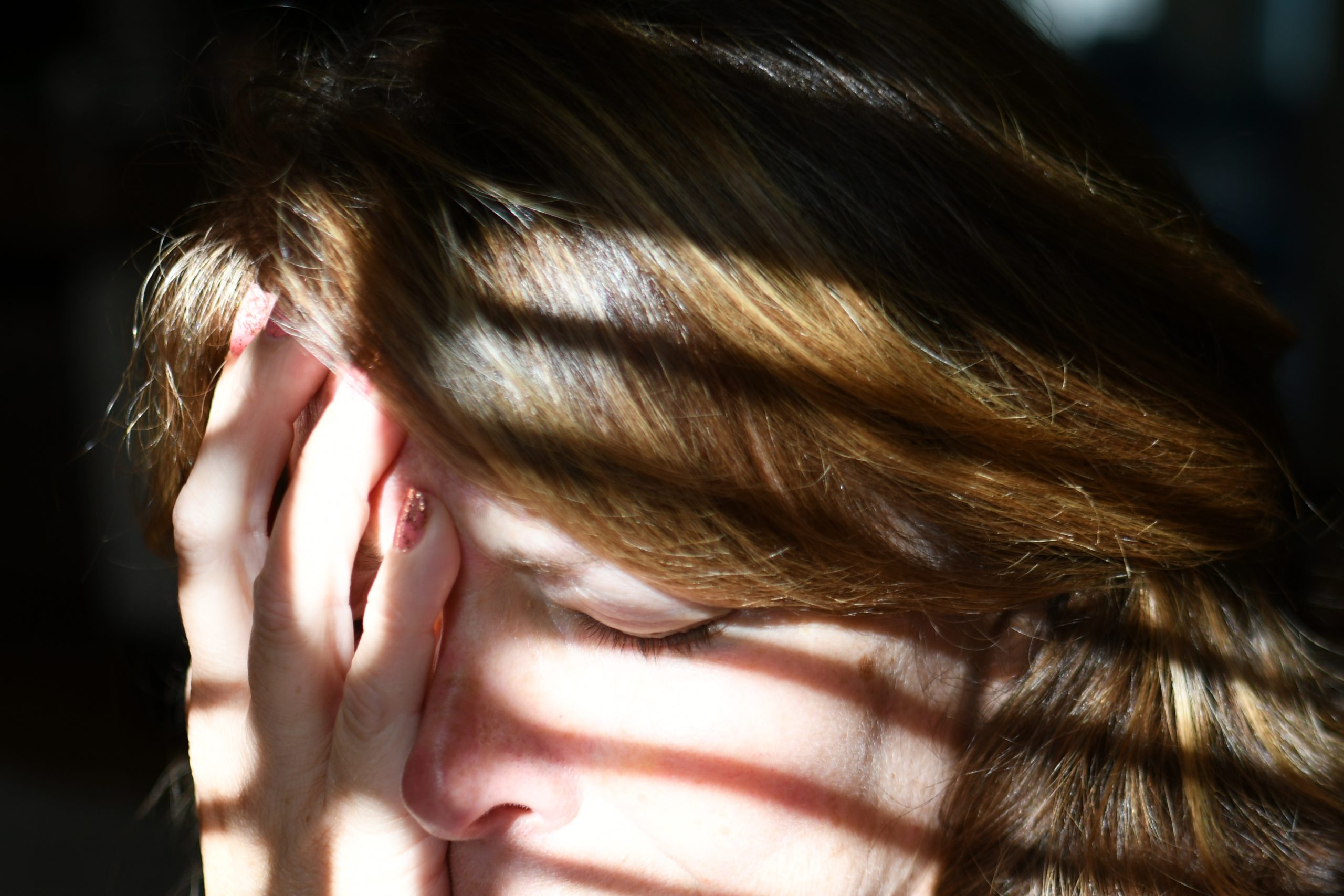 Woman holds face in hands.