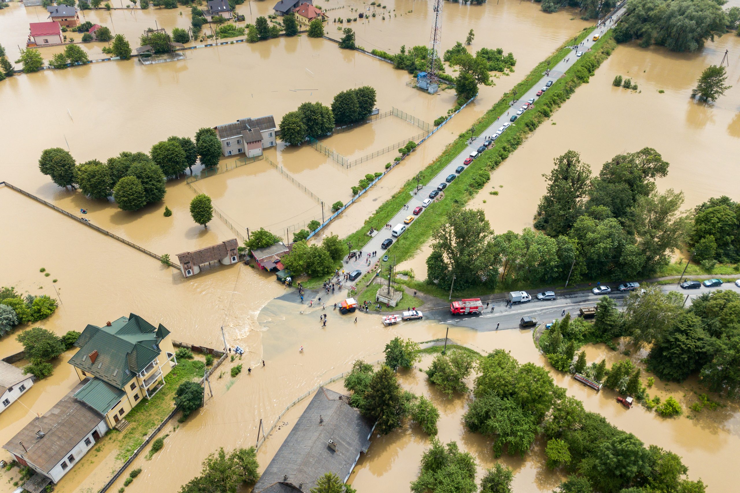 Aerial view of flooded houses and rescue vehicles saving people.