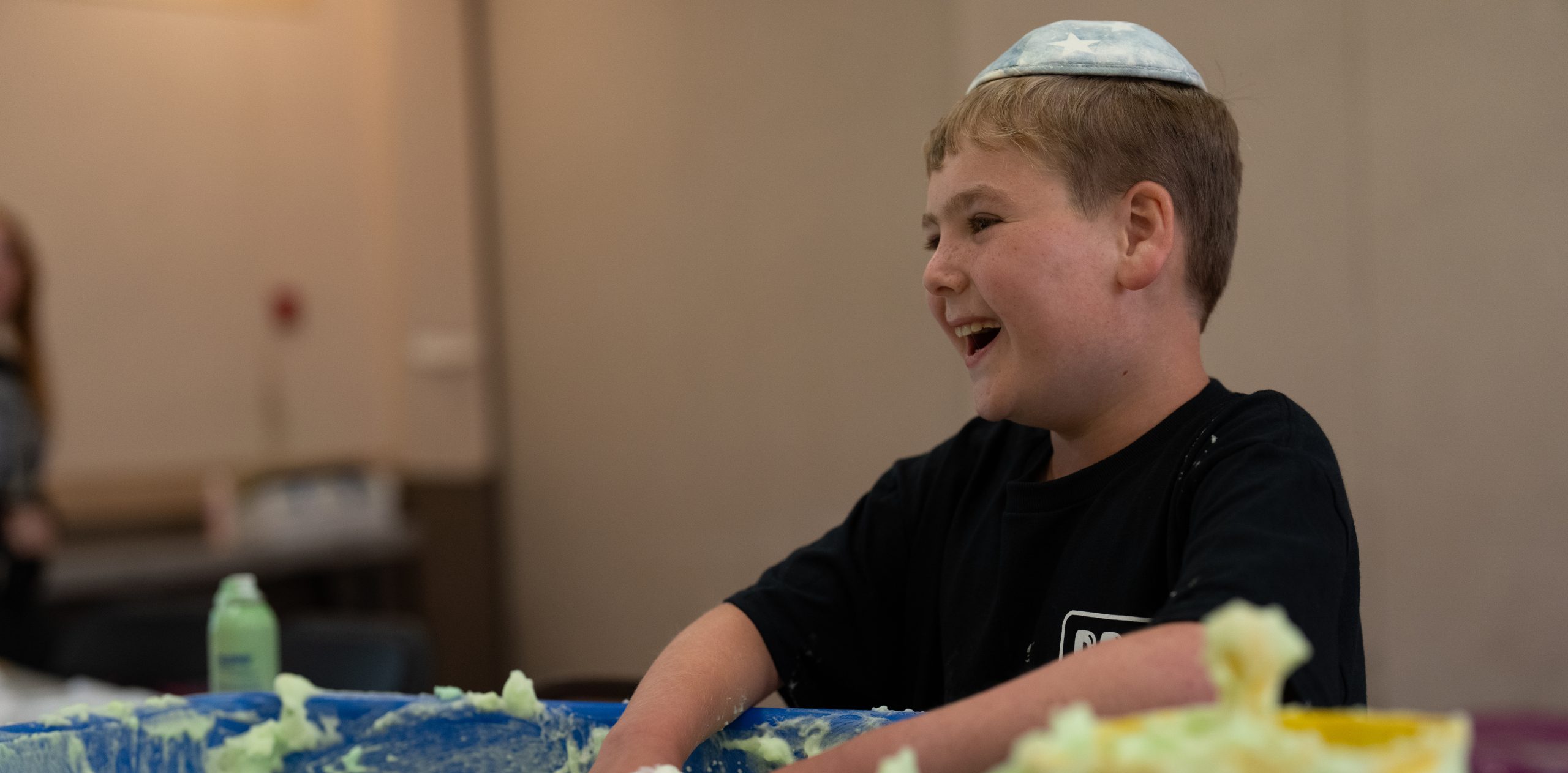 Smiling jewish child plays with a sensory bin.