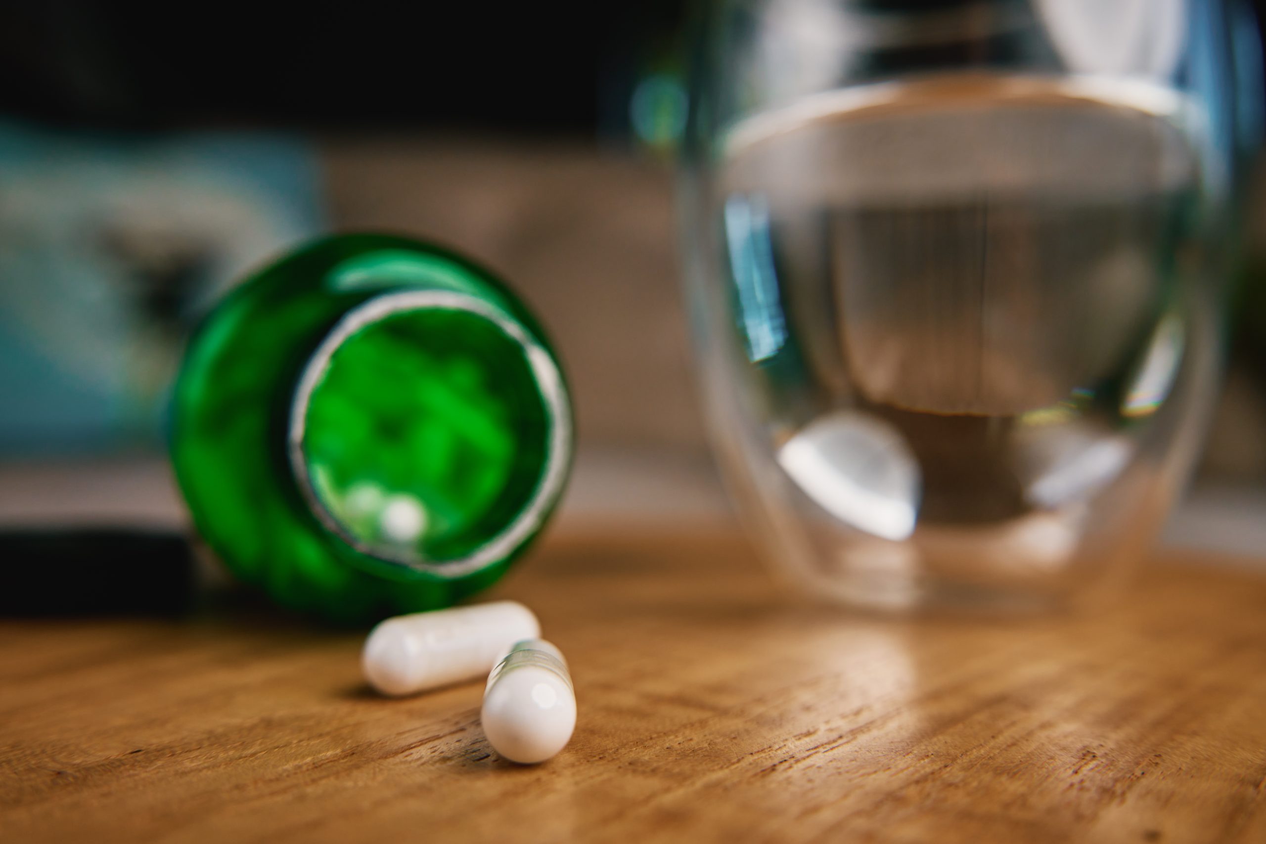 Pill Bottle spilling onto table and with glass Of water.