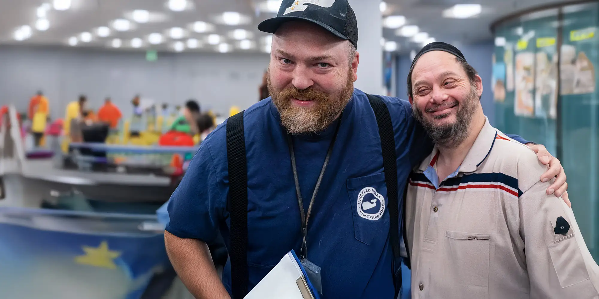 Two smiling men stand side by side in an entertainment center.