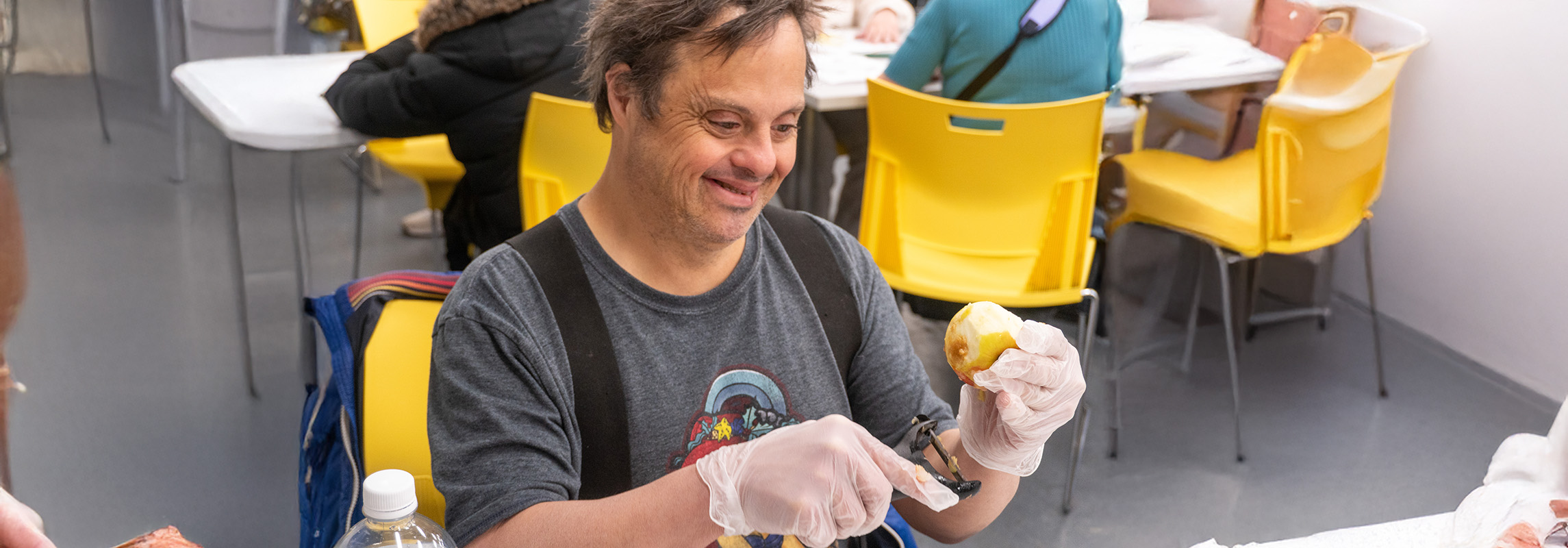 Smiling man with Developmental Disability peels apple.