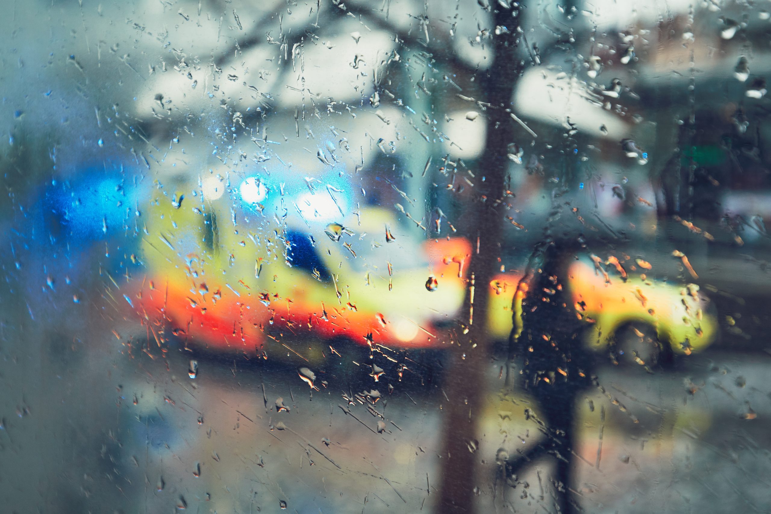 Ambulance on street with view blurred by rainy windows.