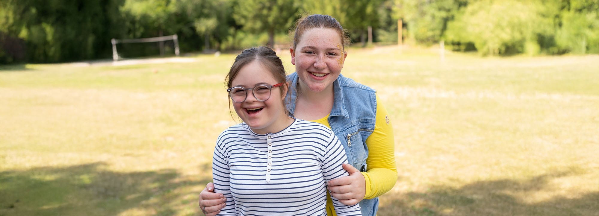 2 young women smiling in a field.